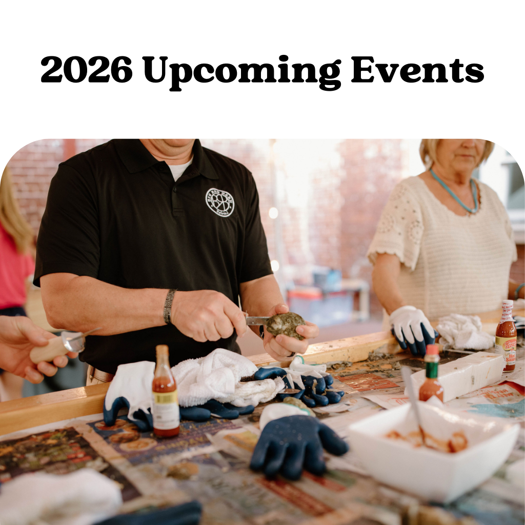 People preparing oysters at a table for a 2026 upcoming event, with sauces and gloves visible.