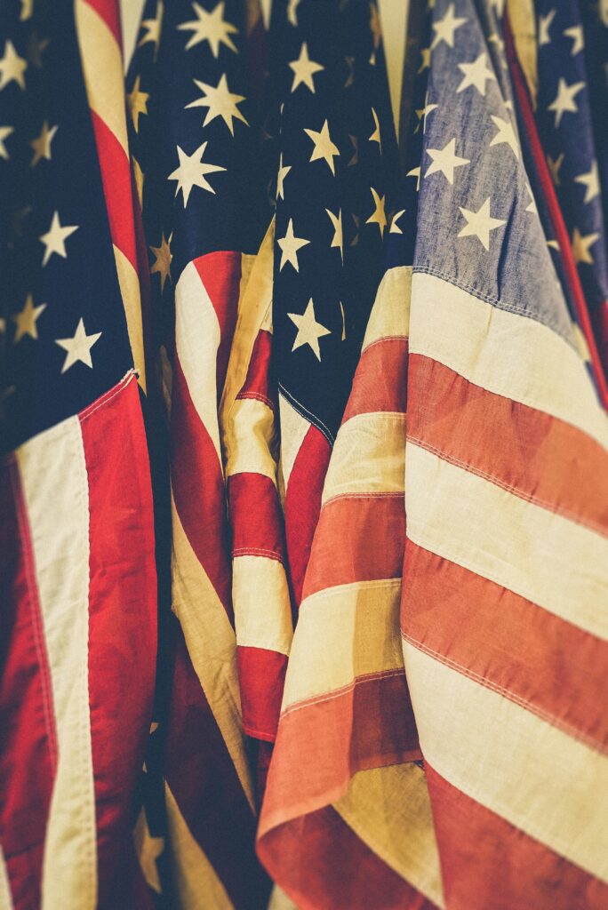 Several faded and closely grouped American flags with visible stars and stripes.