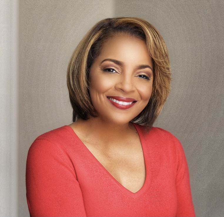 Woman with short, highlighted hair wearing a red top, smiling and posing against a neutral background.