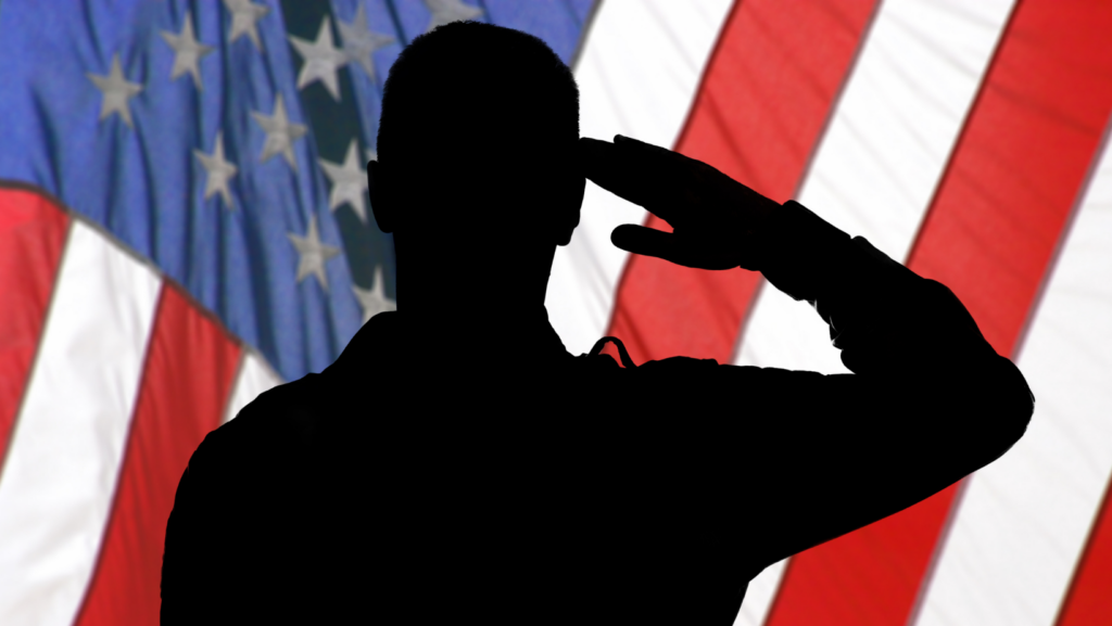 Silhouette of a person saluting in front of an American flag background.