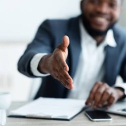 Partnership concept. Smiling young African American businessman extending hand to shake.